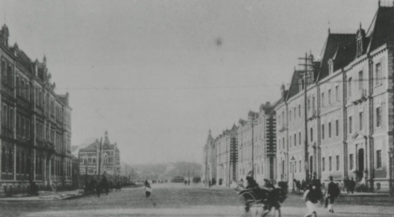 Old black-and-white street lined with multi-storey brick office buildings, a horse-drawn carriage in the foreground