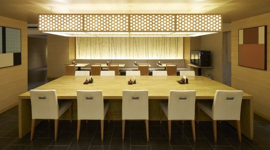 Mitsubishi Corporation: Long wooden dining table under a glowing latticed ceiling
