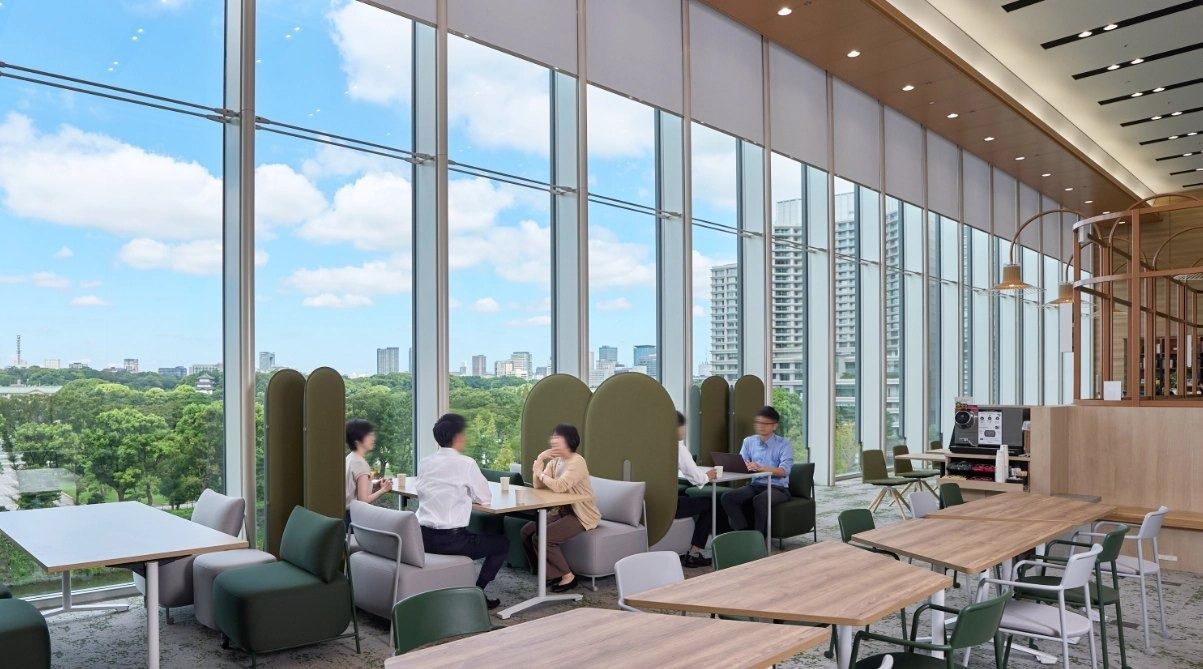 Mitsubishi Corporation: Lounge with pod seats and tables beside tall windows over trees