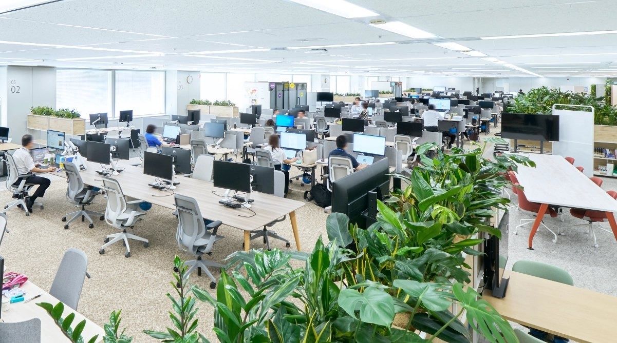 Mitsubishi Corporation: Open office with many desks and plants in the foreground