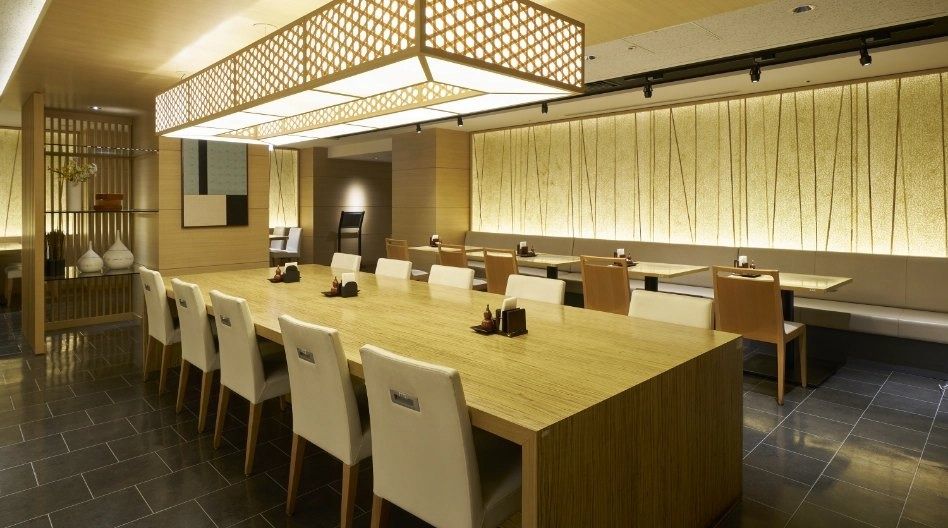 Mitsubishi Corporation: Wooden tables and chairs along a lit wall