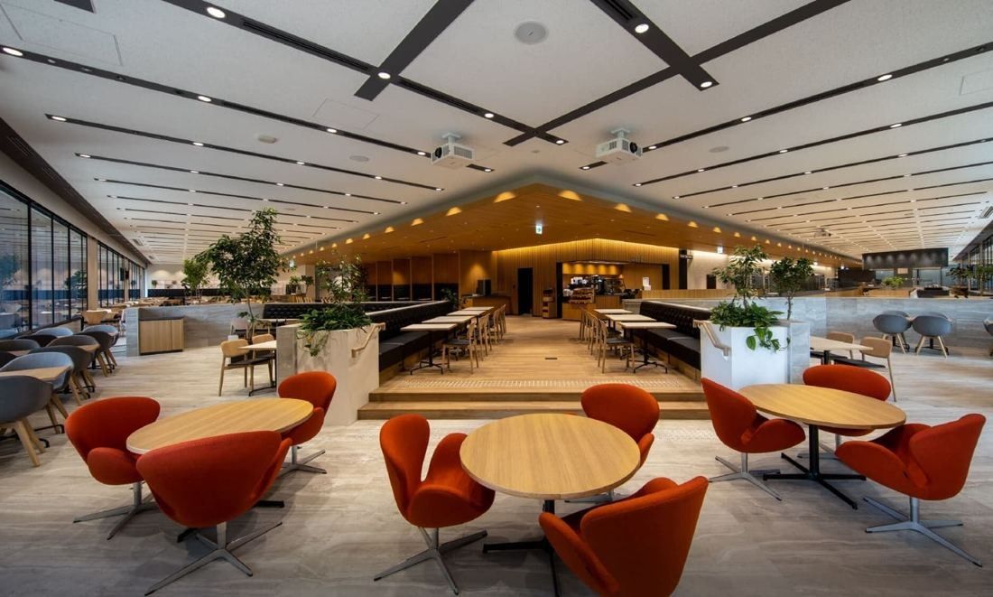 Mitsui & Co.: Dining space with round tables, red chairs and a slatted ceiling