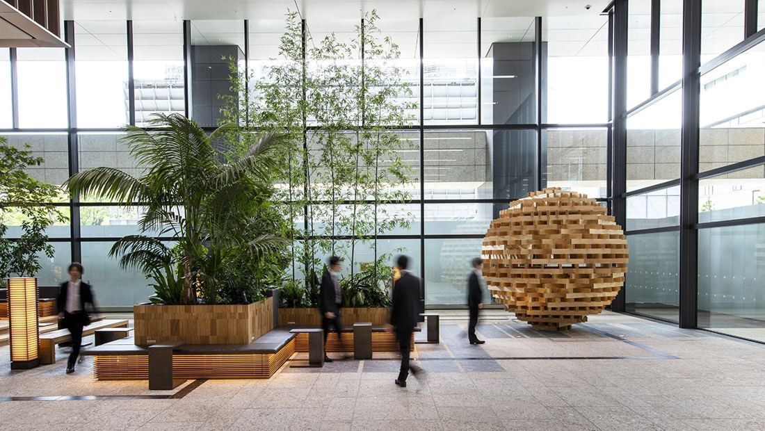 Mitsui & Co.: Glass-walled atrium with large planters and a spherical wooden sculpture