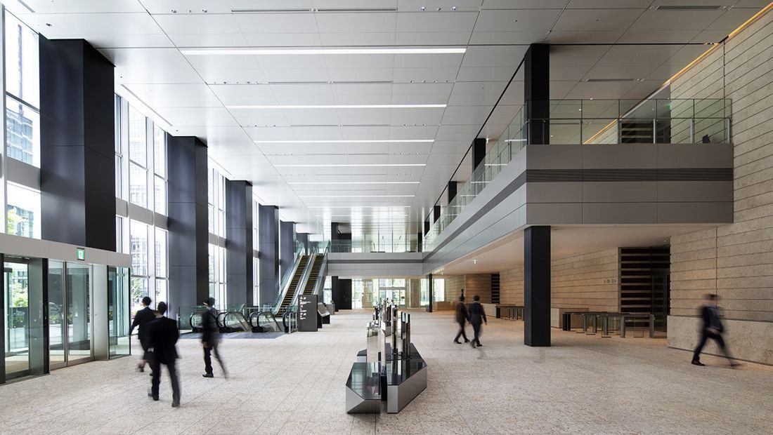 Mitsui & Co.: High lobby with stone walls, escalators and glass doors, people walking