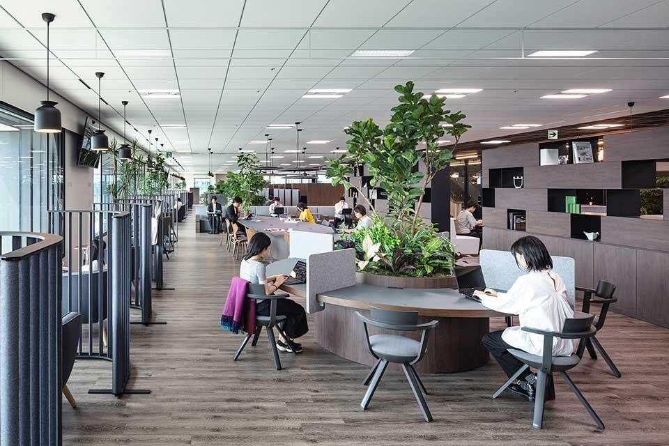 Mitsui & Co.: Long floor with round desks around a planter and partitioned seats
