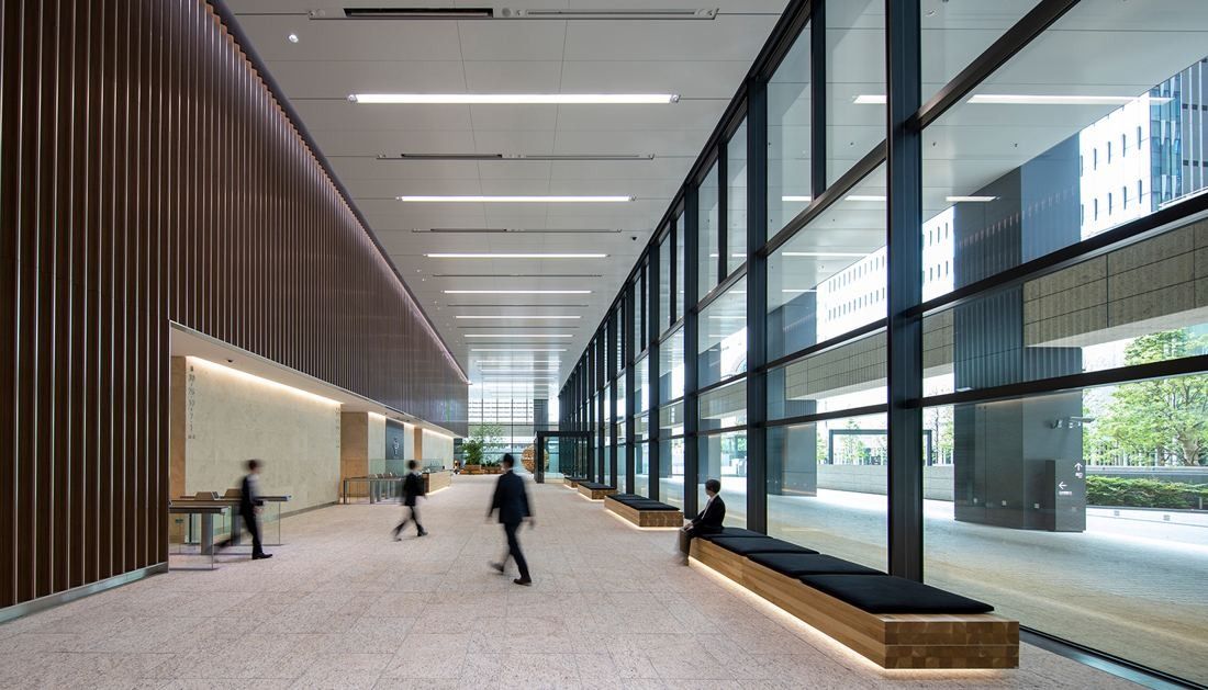 Mitsui & Co.: Long glazed corridor with timber-slatted wall and a cushioned bench
