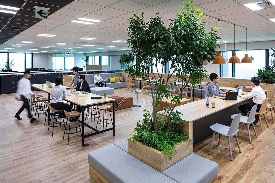 Mitsui & Co.: Open floor with a planter bench, high tables and orange pendant lamps