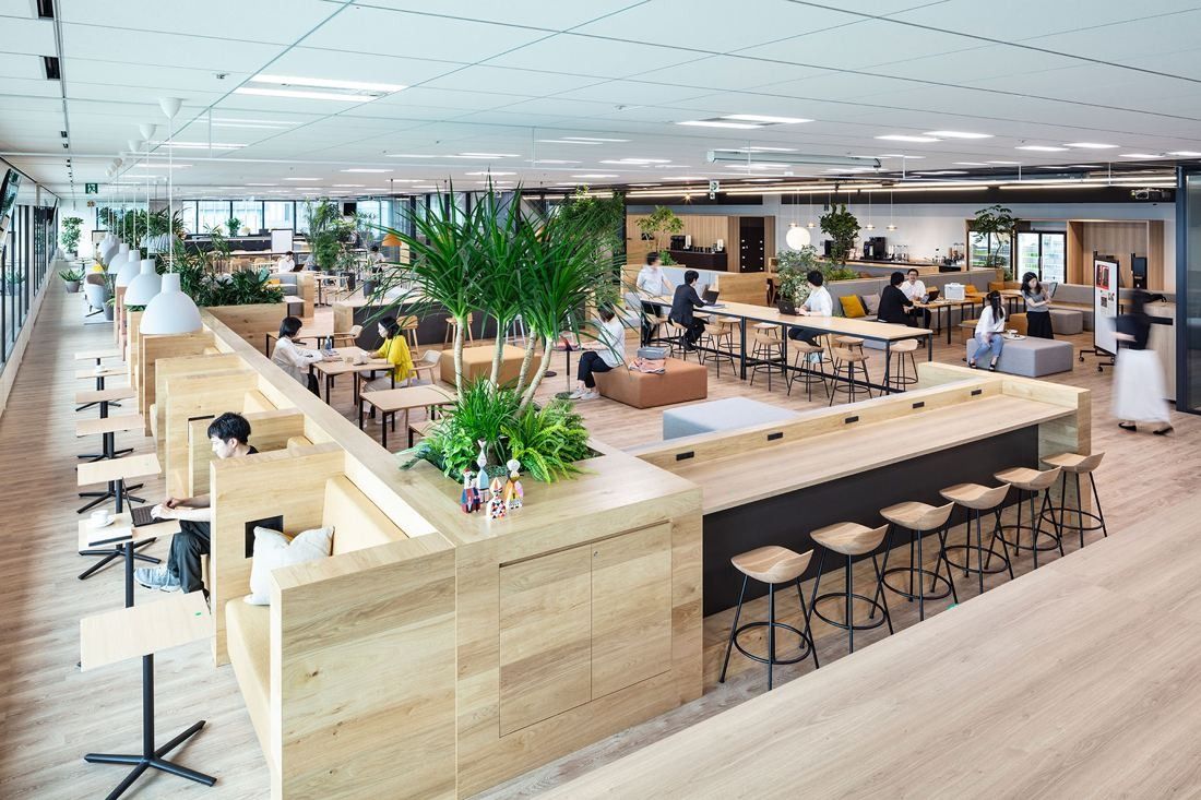 Mitsui & Co.: Open office floor with wooden booths, a bar counter with stools and large plants