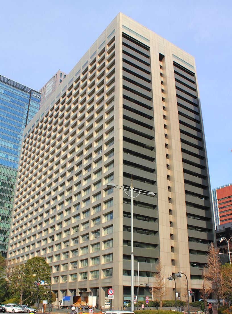 Pale grid-faced office tower under a blue sky