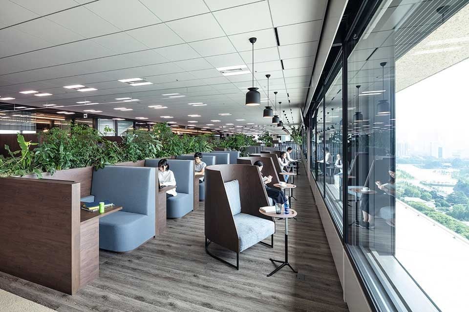 Mitsui & Co.: Row of high-backed booths along a glass wall overlooking greenery