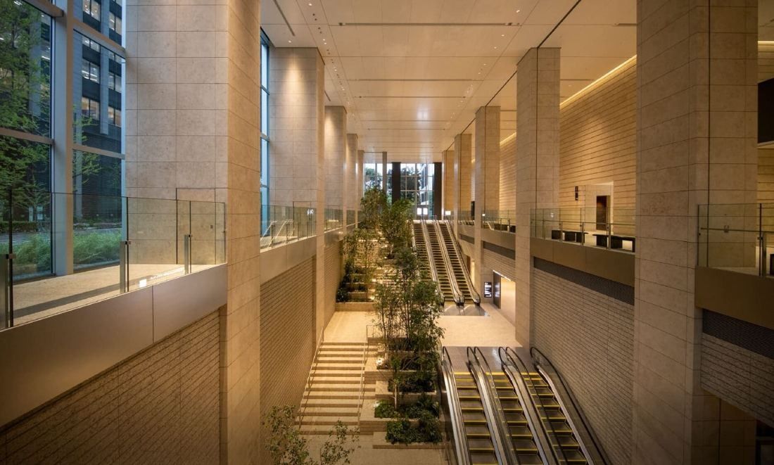 Mitsui & Co.: Tall stone-clad atrium with a planted staircase and escalators