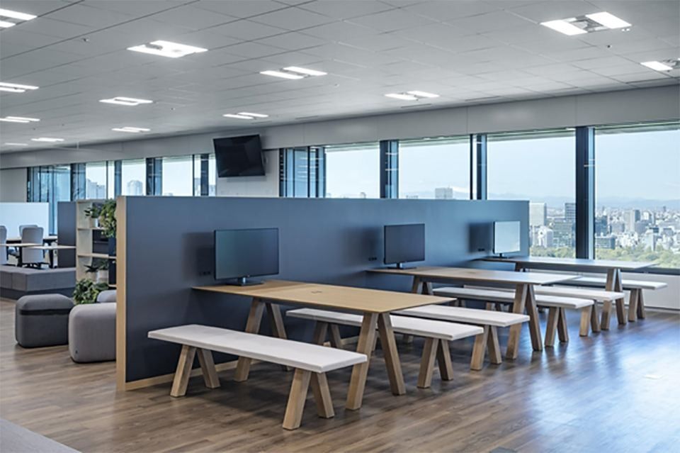 Mitsui & Co.: Wooden tables with benches beside tall windows overlooking the city