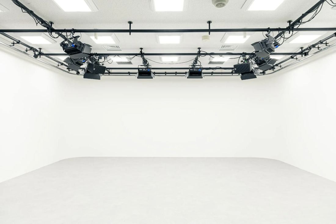 MIXI: Empty white photo studio with lighting rigs on the ceiling