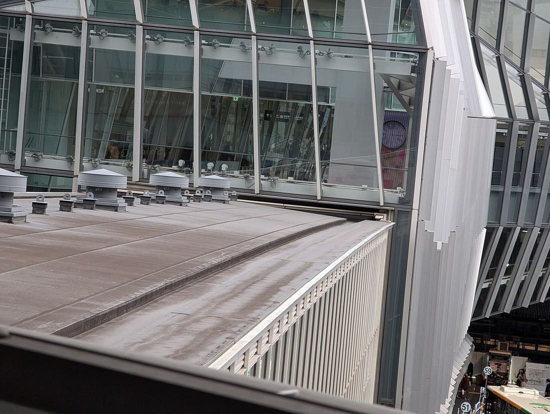MIXI: Glass façade of a tower seen across station roofs