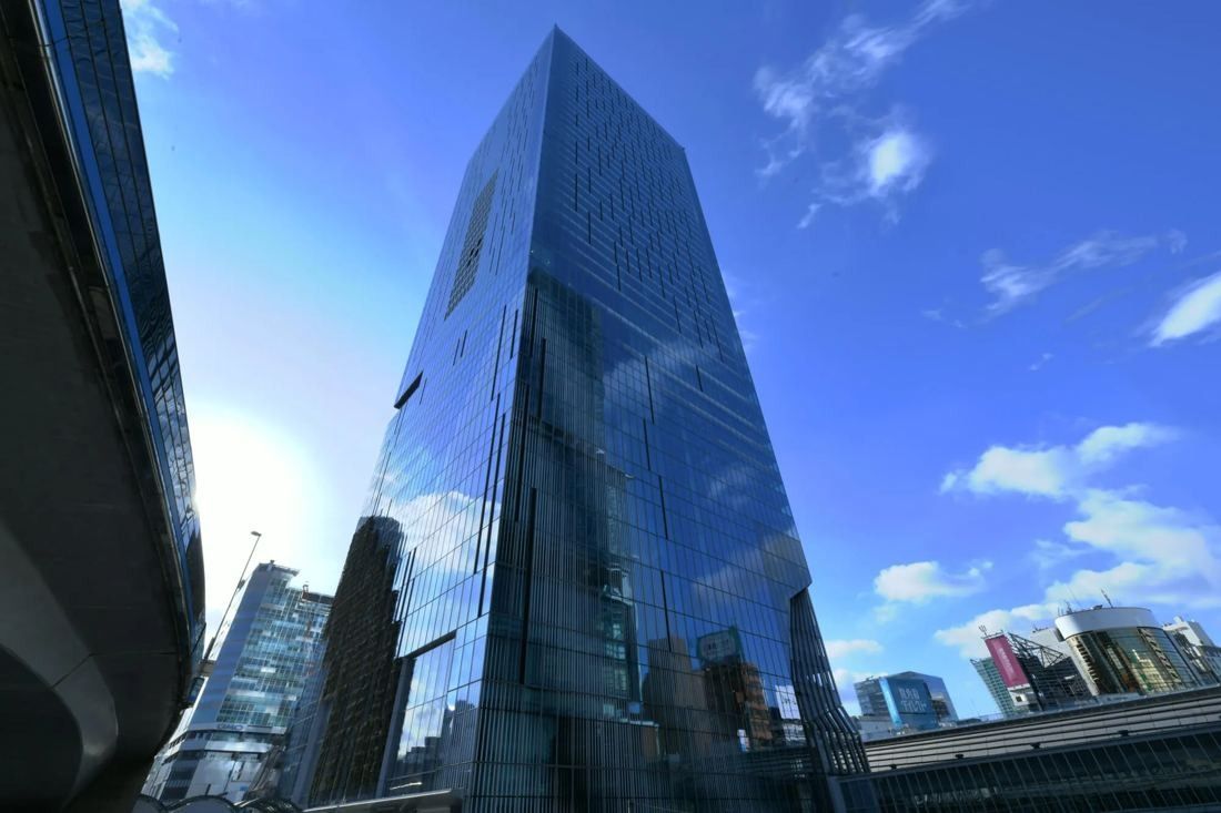 Low-angle view of a tall glass tower against a blue sky