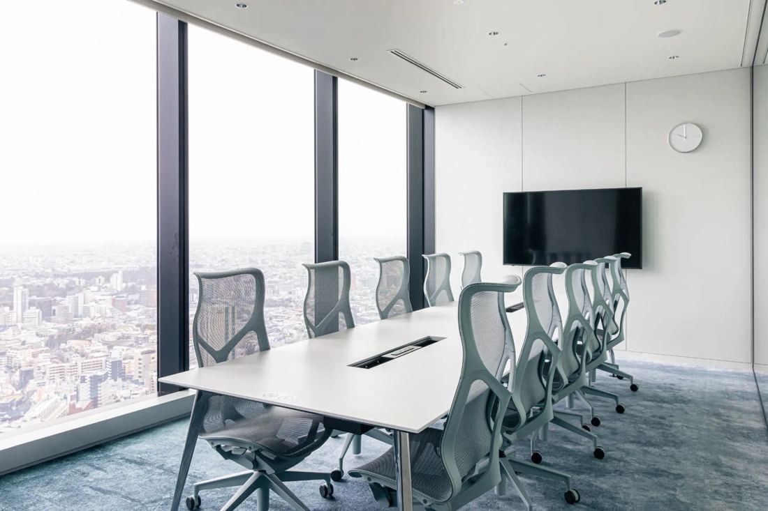 MIXI: Meeting room with white table, grey chairs and floor-to-ceiling windows over the city