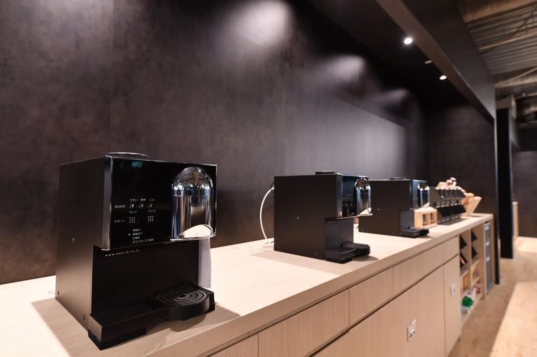 MIXI: Row of coffee machines on a white counter against a black wall