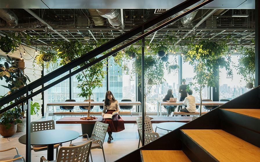 MIXI: Steel staircase beside a planted café seating area with city views