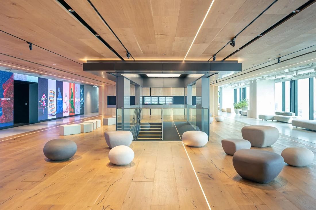 MIXI: Wood-floored reception hall with pebble-shaped seats and a glass stair enclosure