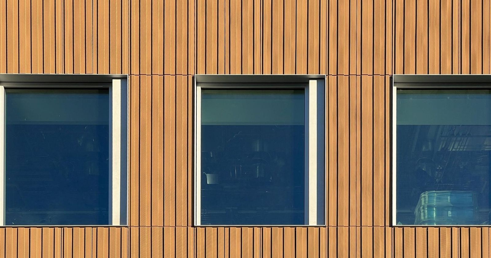 Moderna: Close-up of timber-toned panels between windows