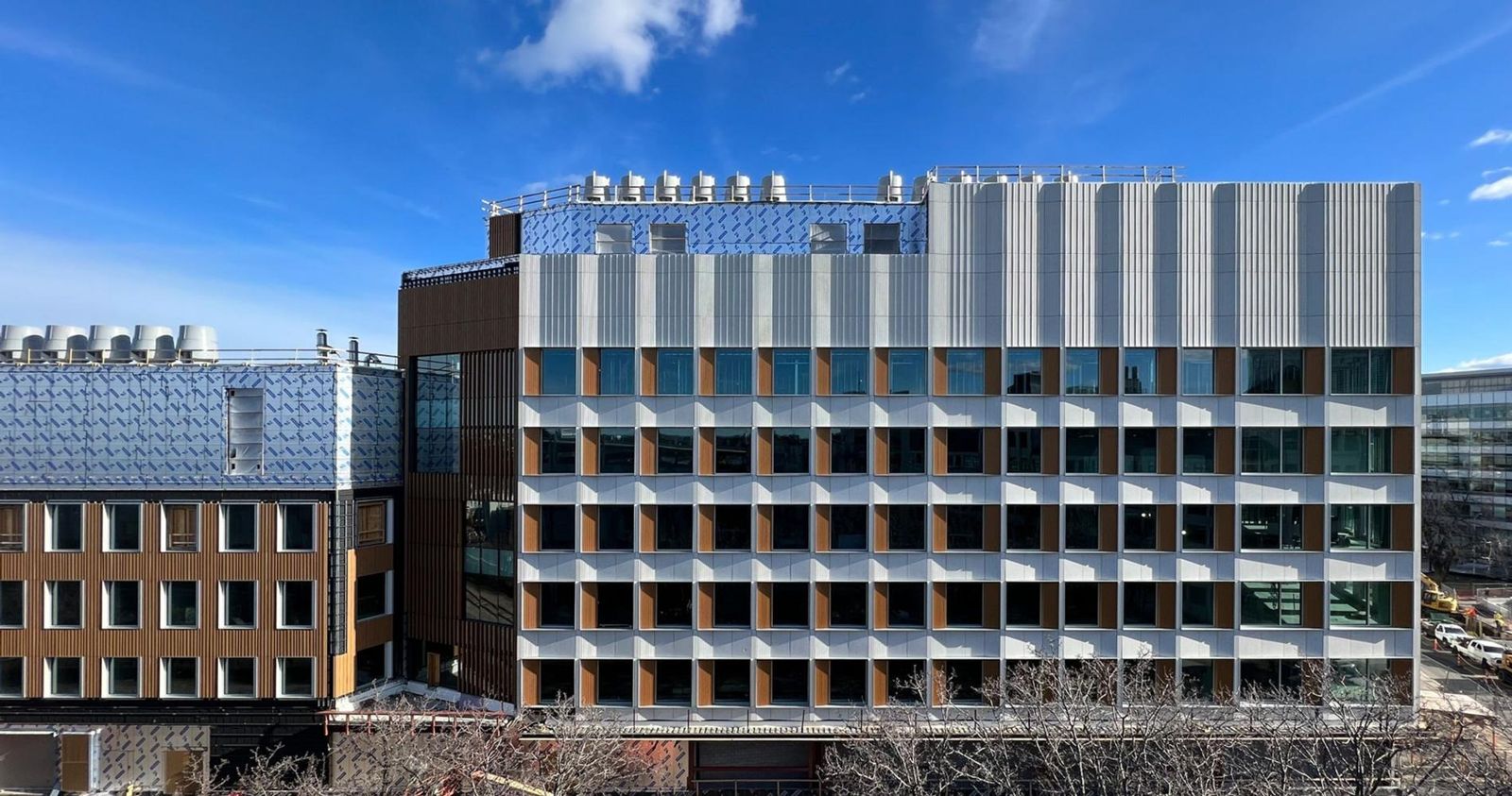Moderna: Facade of white panels and timber-toned fins under a blue sky