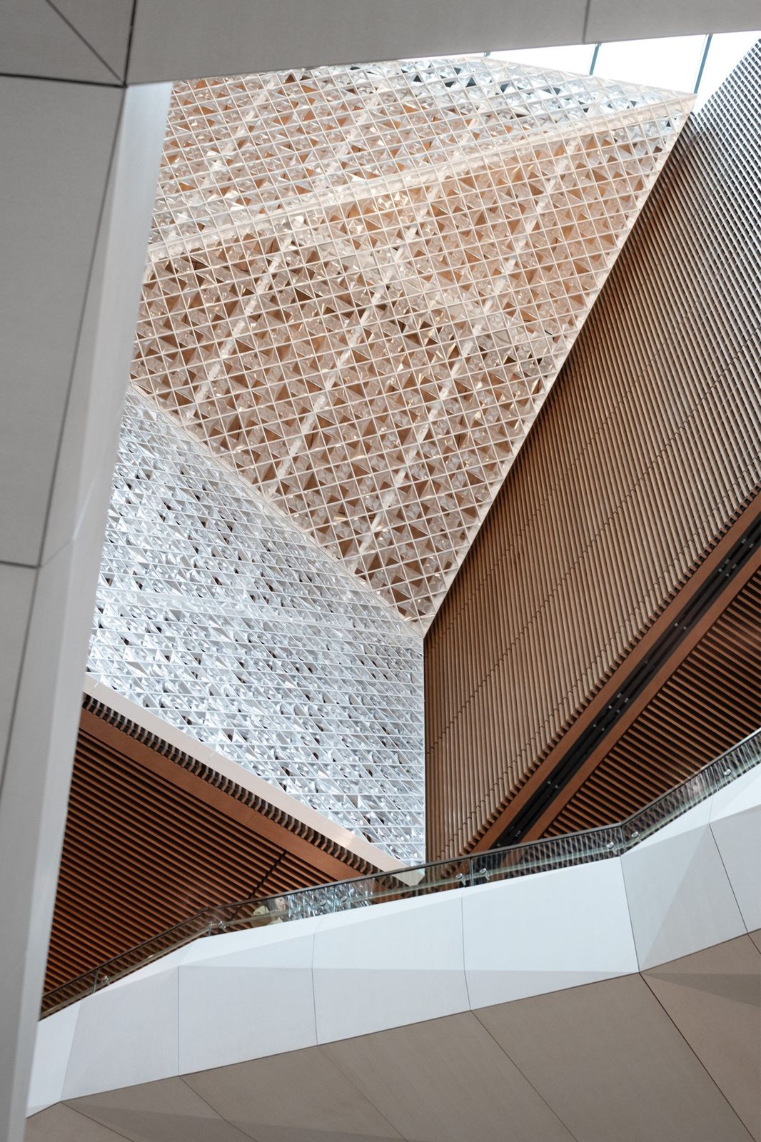 Moderna: Faceted wall of white perforated panels over timber