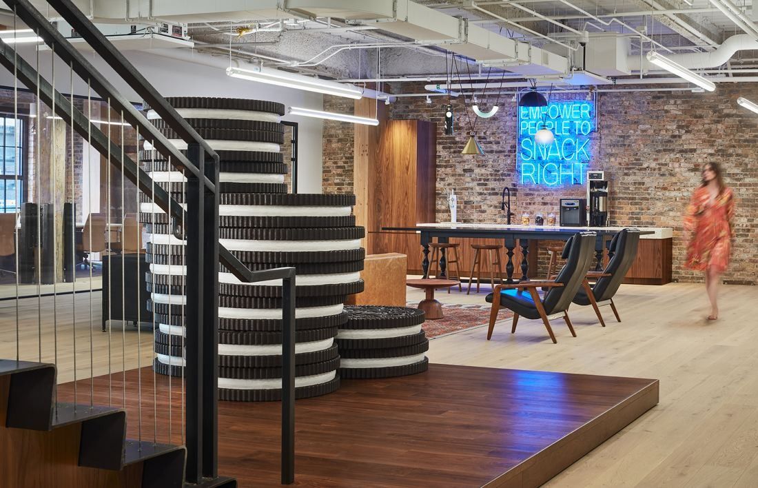 Mondelēz International: Black-and-white striped spiral stair on a wooden platform, with a neon sign and seating behind