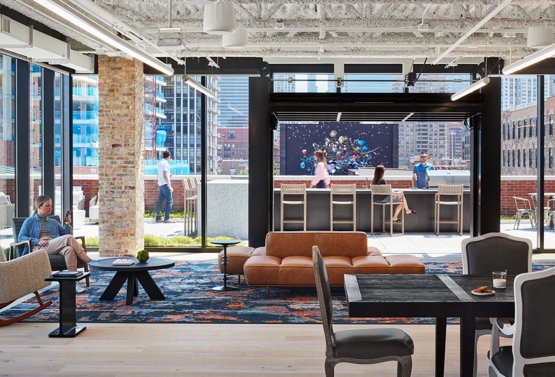 Mondelēz International: Lounge with orange sofas and a bar under a steel frame, opening onto a planted terrace and city towers