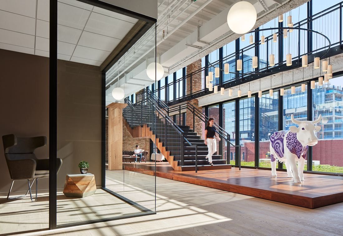 Mondelēz International: Steel stair rising beside tall windows, with a cow sculpture on a wooden platform in front
