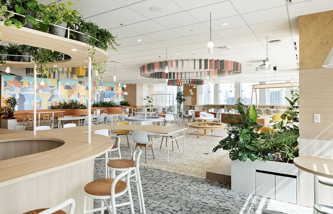 Money Forward: Curved wooden counter with stools beneath a ring of hanging panels and plants