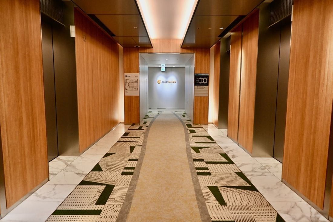 Money Forward: Elevator hall with wood-panelled walls and a patterned runner carpet