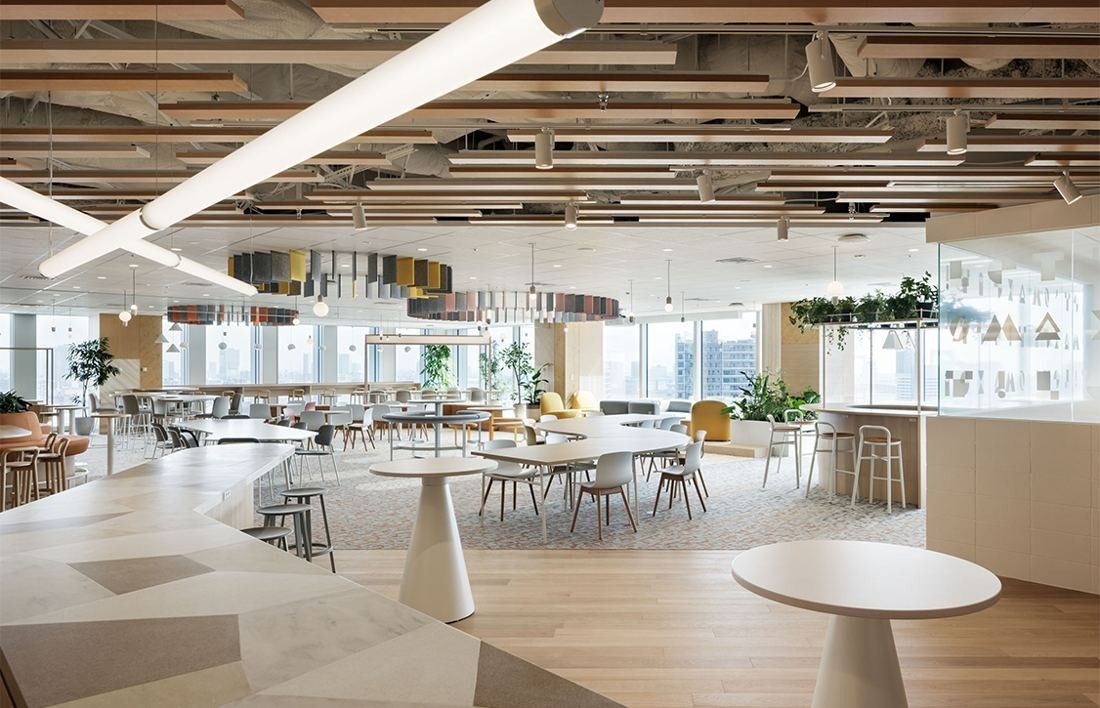 Money Forward: Large open lounge with round white tables, a timber-slatted ceiling and city views through the windows