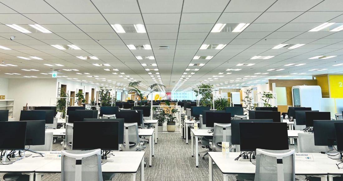 Money Forward: Long rows of desks with black monitors and grey chairs across an open floor