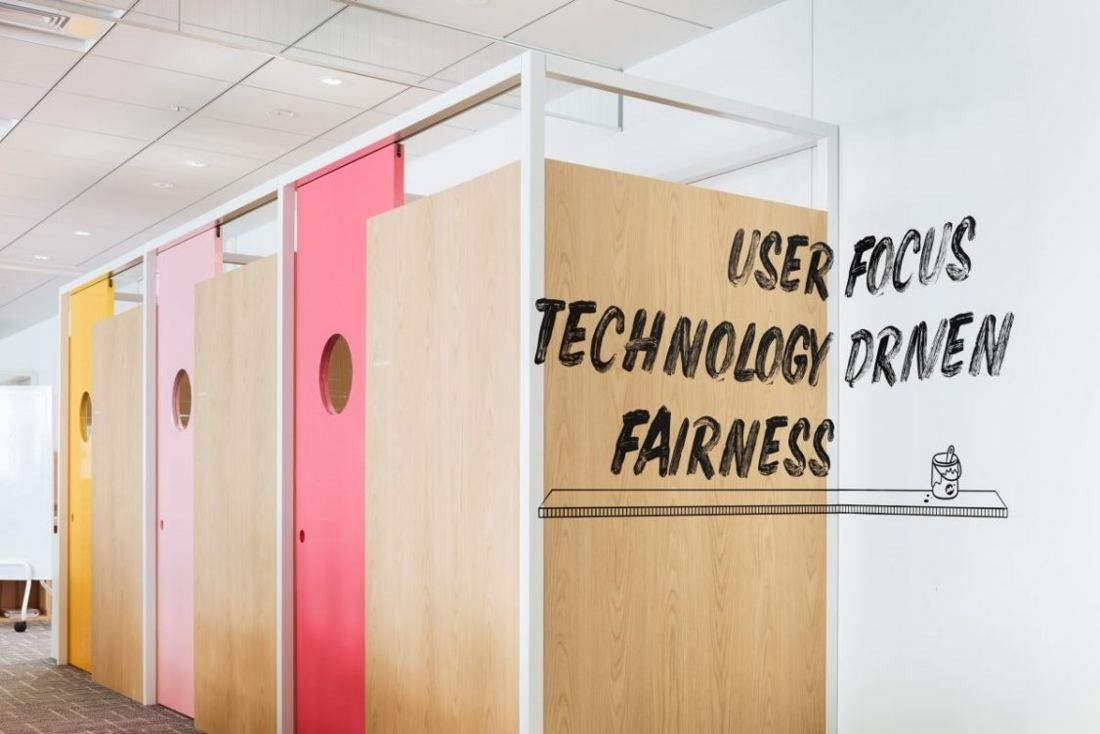 Money Forward: Row of pastel-coloured doors with round windows next to a wall lettered with words