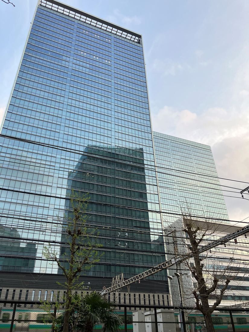 Money Forward: Two glass office towers seen from the street, with a taller tower in the background