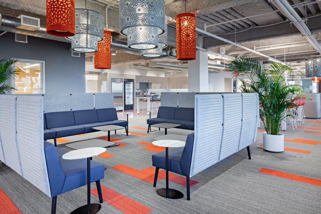 MongoDB: Blue sofas and small round tables between white partitions under patterned pendant lamps