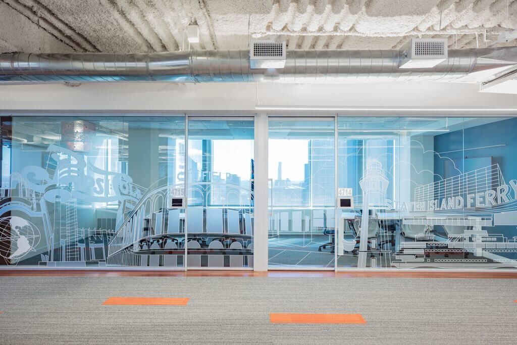 MongoDB: Row of glass-walled rooms decorated with New York-themed line graphics, windows beyond