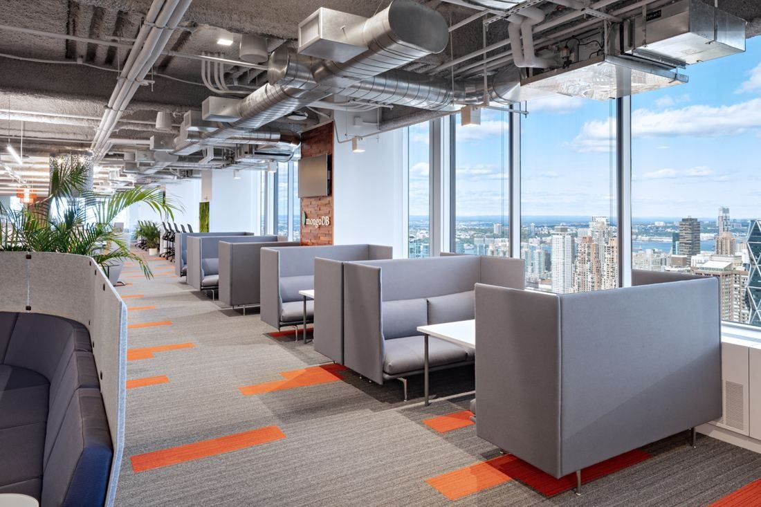 MongoDB: Row of grey high-backed booths along a window wall with orange accents in the carpet and views over Manhattan