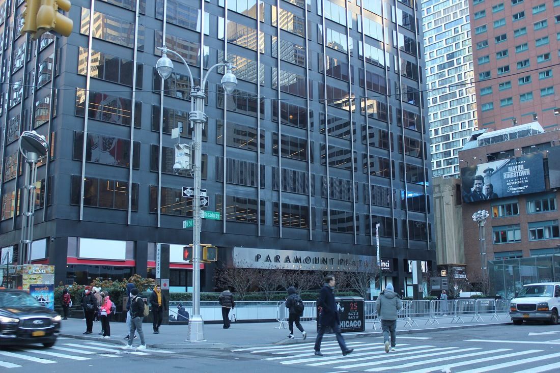 MongoDB: Street corner view of the base of a dark office tower with a Paramount Plaza sign and pedestrians crossing