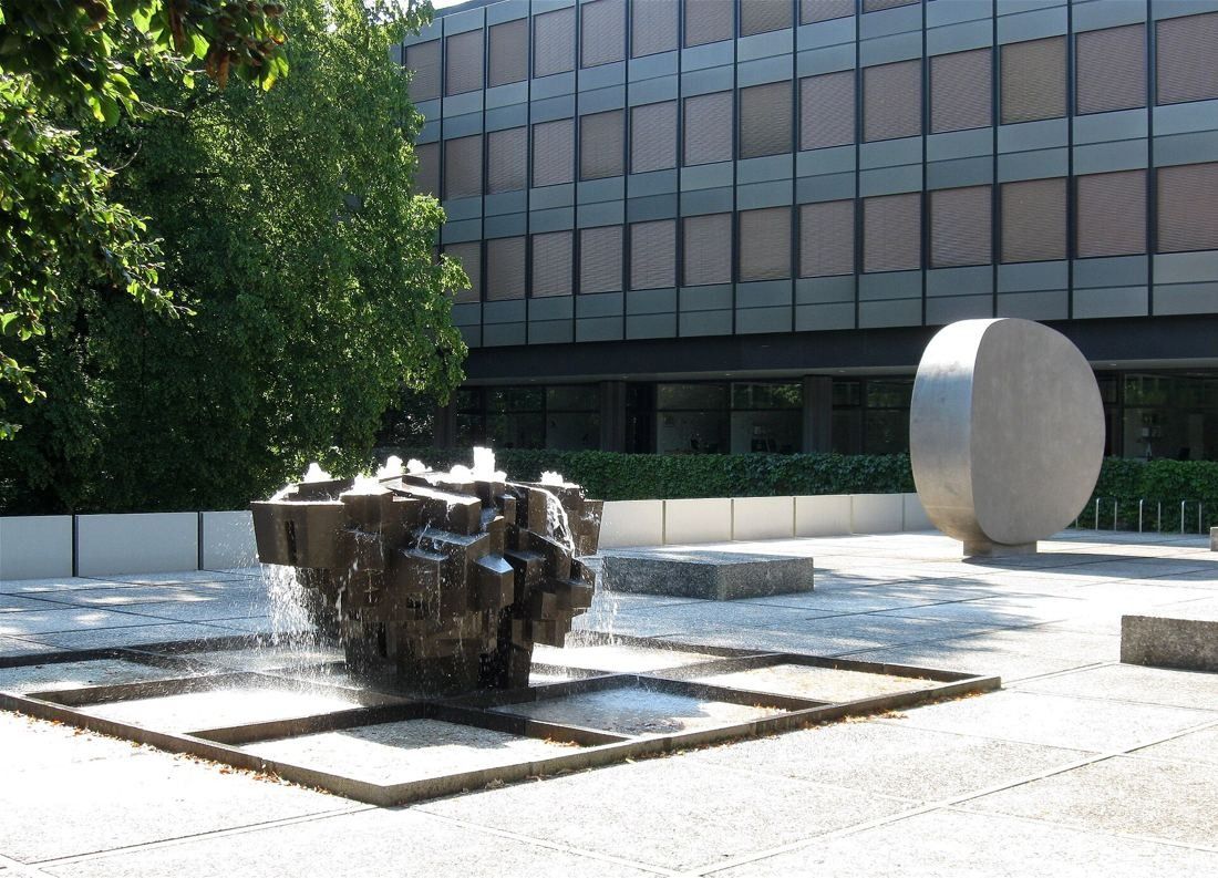 Munich Re: Bronze fountain of stacked blocks in a paved courtyard in front of an office block