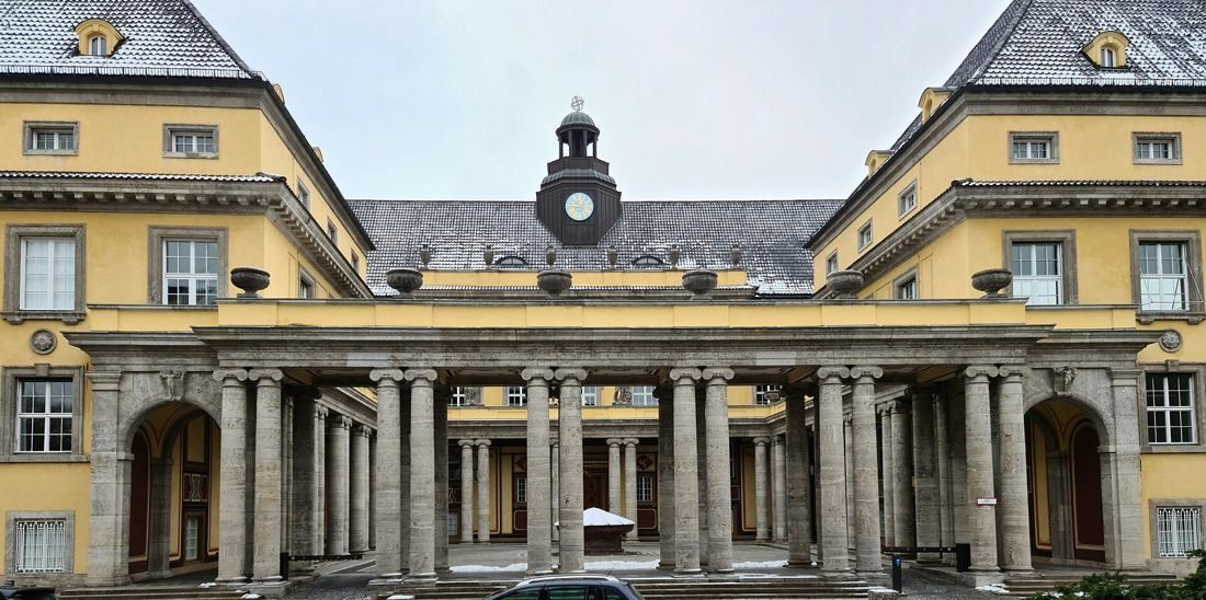 Munich Re: Columned screen with arches opening from the street into a courtyard, clock turret behind
