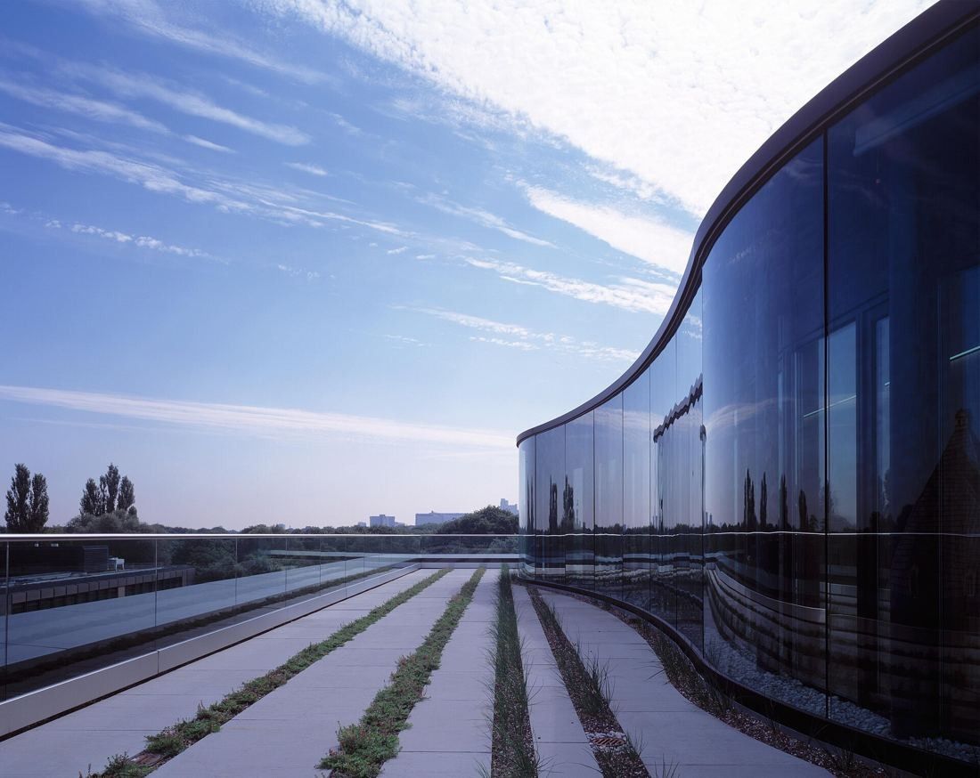 Munich Re: Curved green glass façade beside a roof terrace with strips of planting