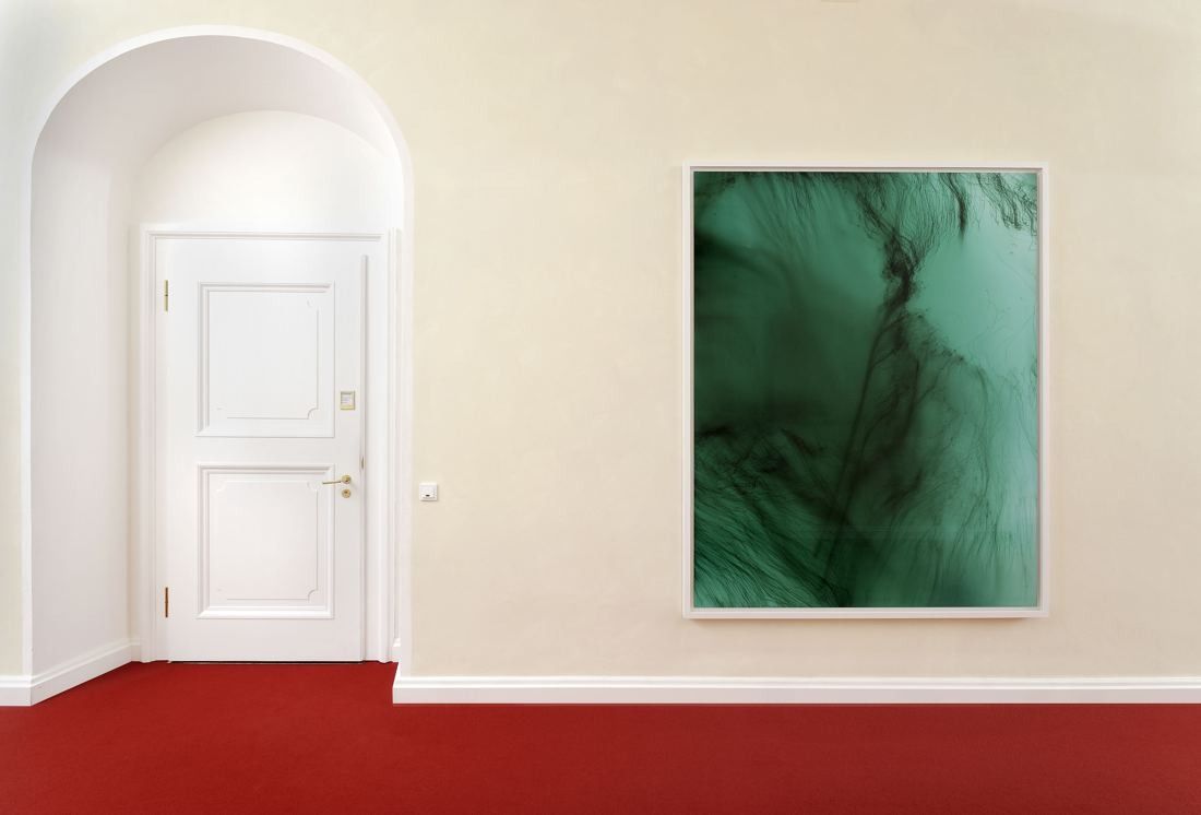 Munich Re: Green abstract photograph hanging in a corridor with a red carpet