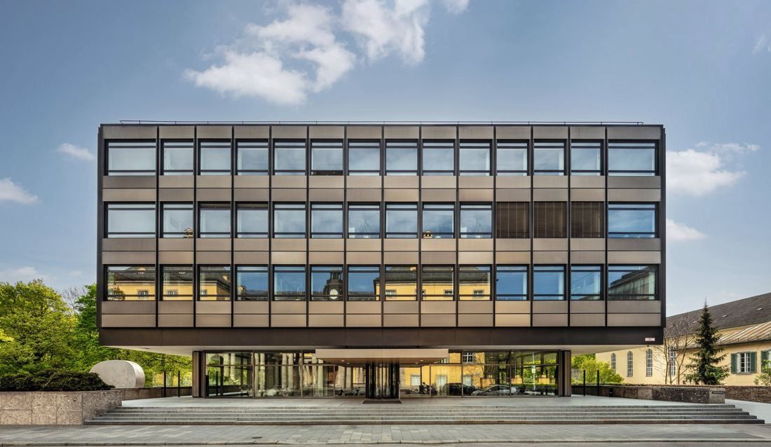 Munich Re: Office block with a dark suspended metal and glass façade raised above a glazed ground floor