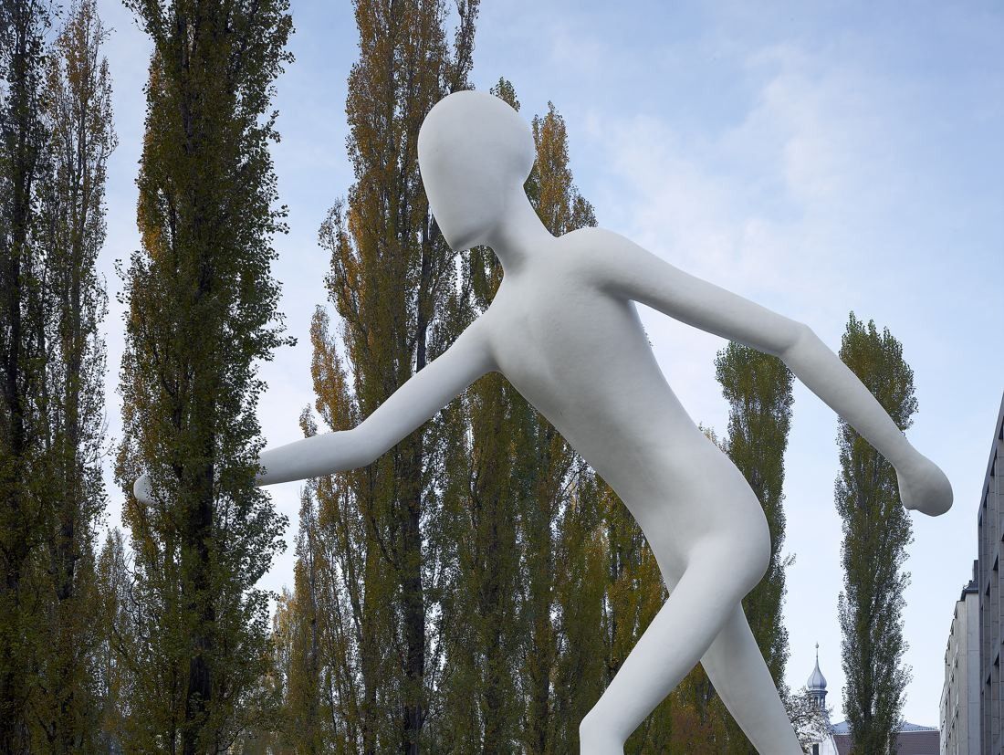 Munich Re: Tall white figure of a walking man against poplar trees