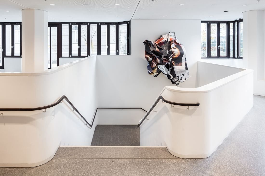 Munich Re: White stairwell with a crumpled metal sculpture on the wall