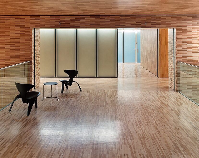 Munich Re: Wood-lined lobby with a polished wooden floor and two black chairs