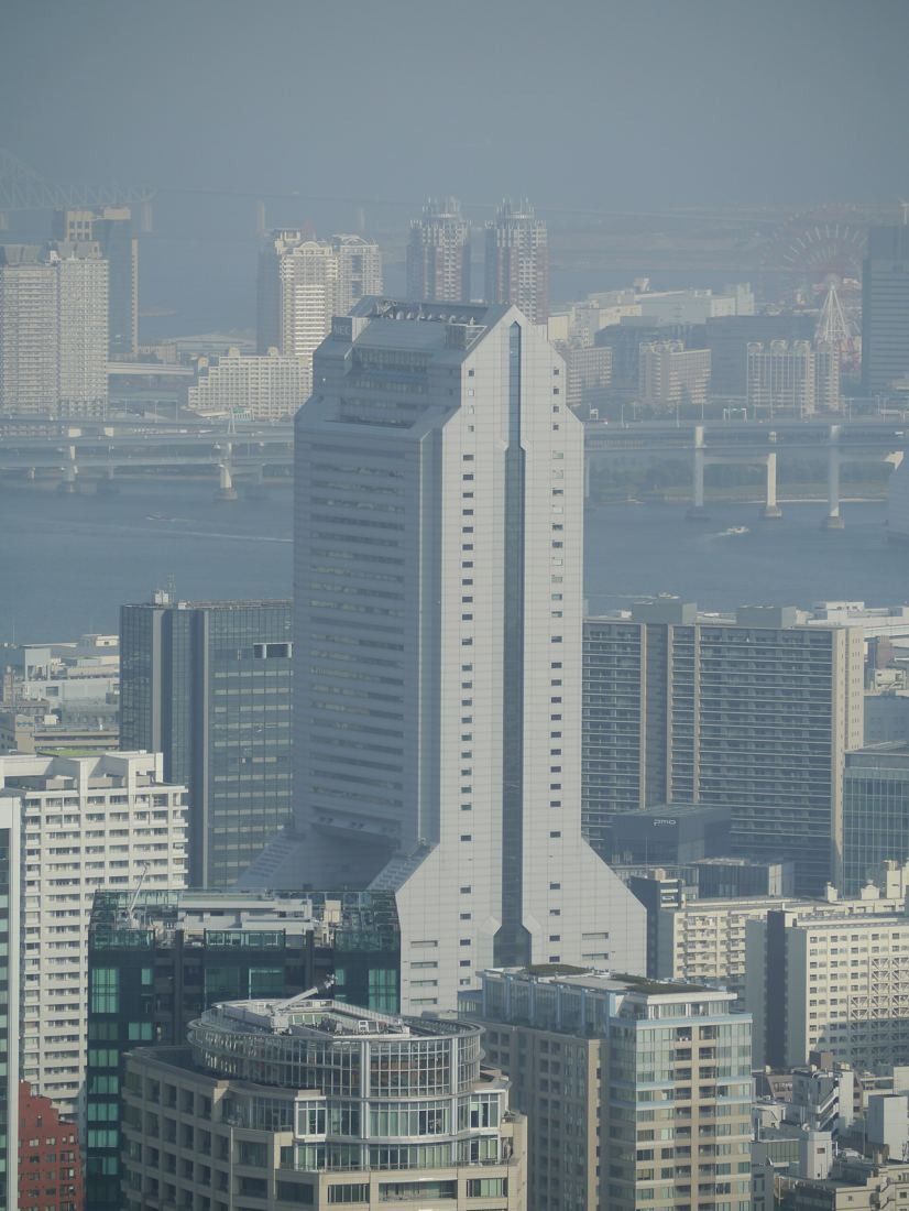 NEC: Hazy distant view of the stepped tower among city buildings