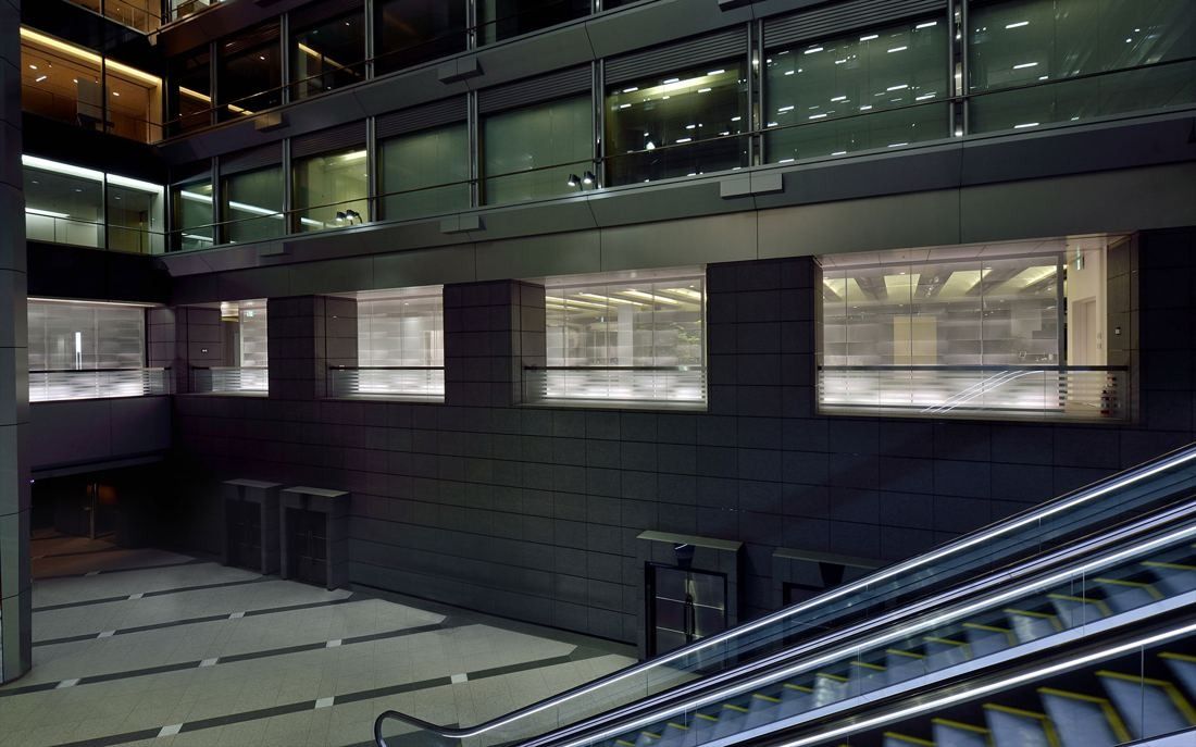 NEC: Multi-storey atrium with dark stone walls, glazed openings and escalators