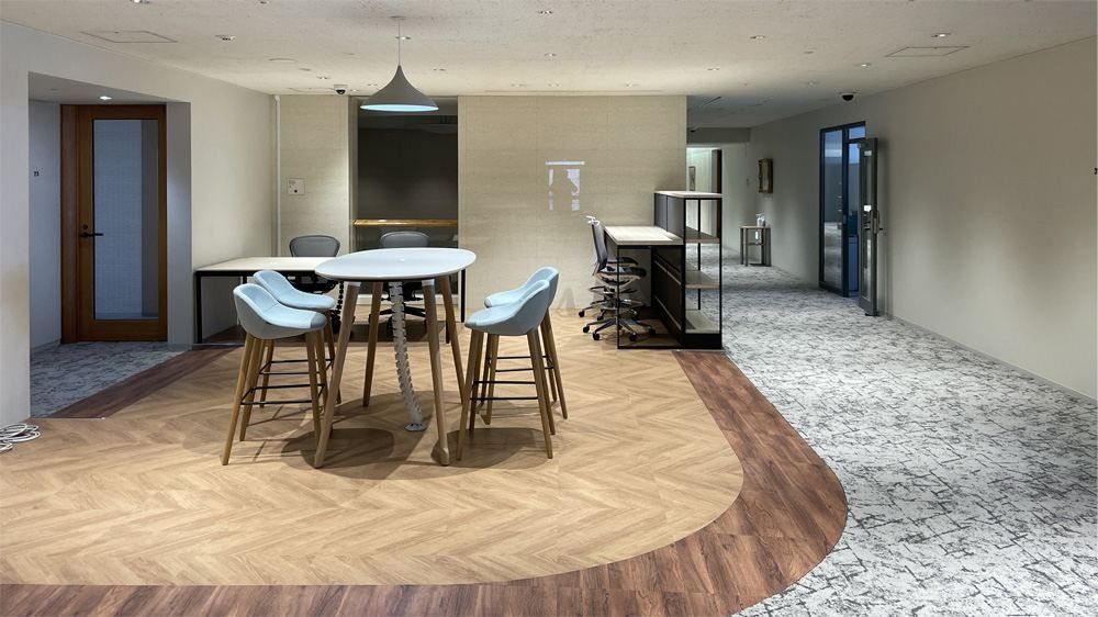 NEC: Round high tables with stools on a curved wood-floor area under pendant lights